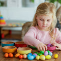 Rainbow nesting bowls set with colorful wooden cups stacked on a table.