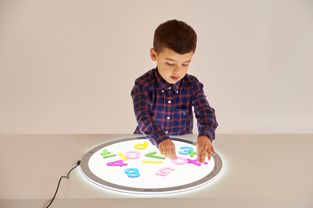 Child placing colorful number tiles on a round light-up number board