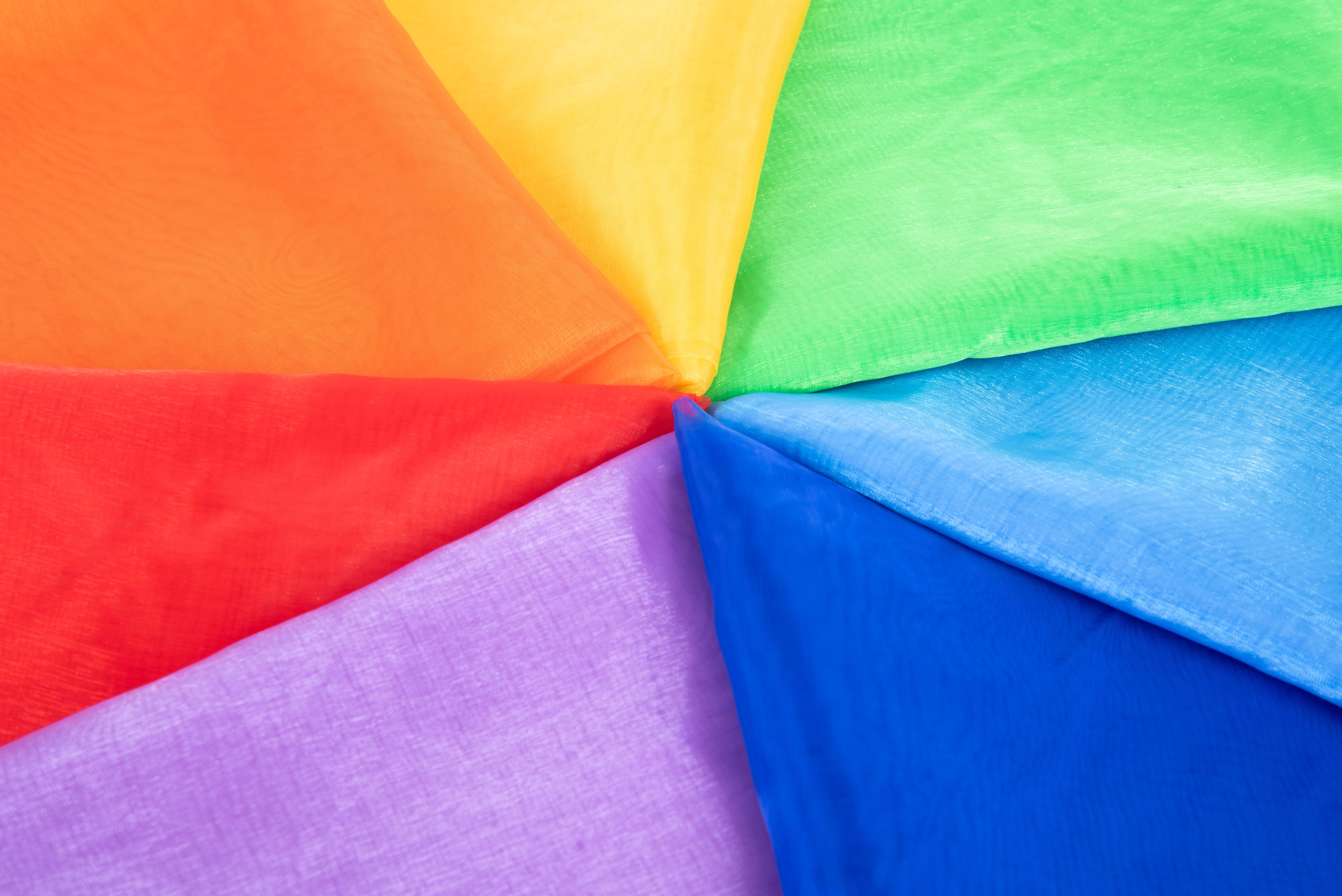 Close-up of folded organza fabric, multicolor panels in red, orange, yellow, green, blue and purple