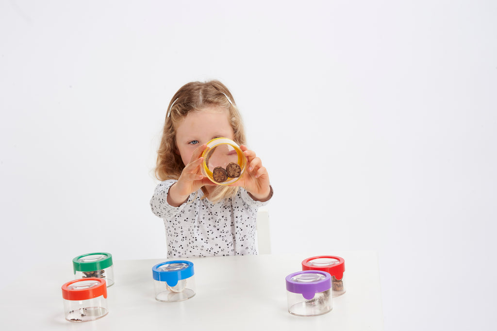 Child holding a yellow-lidded clear viewer magnifier with a bug inside.