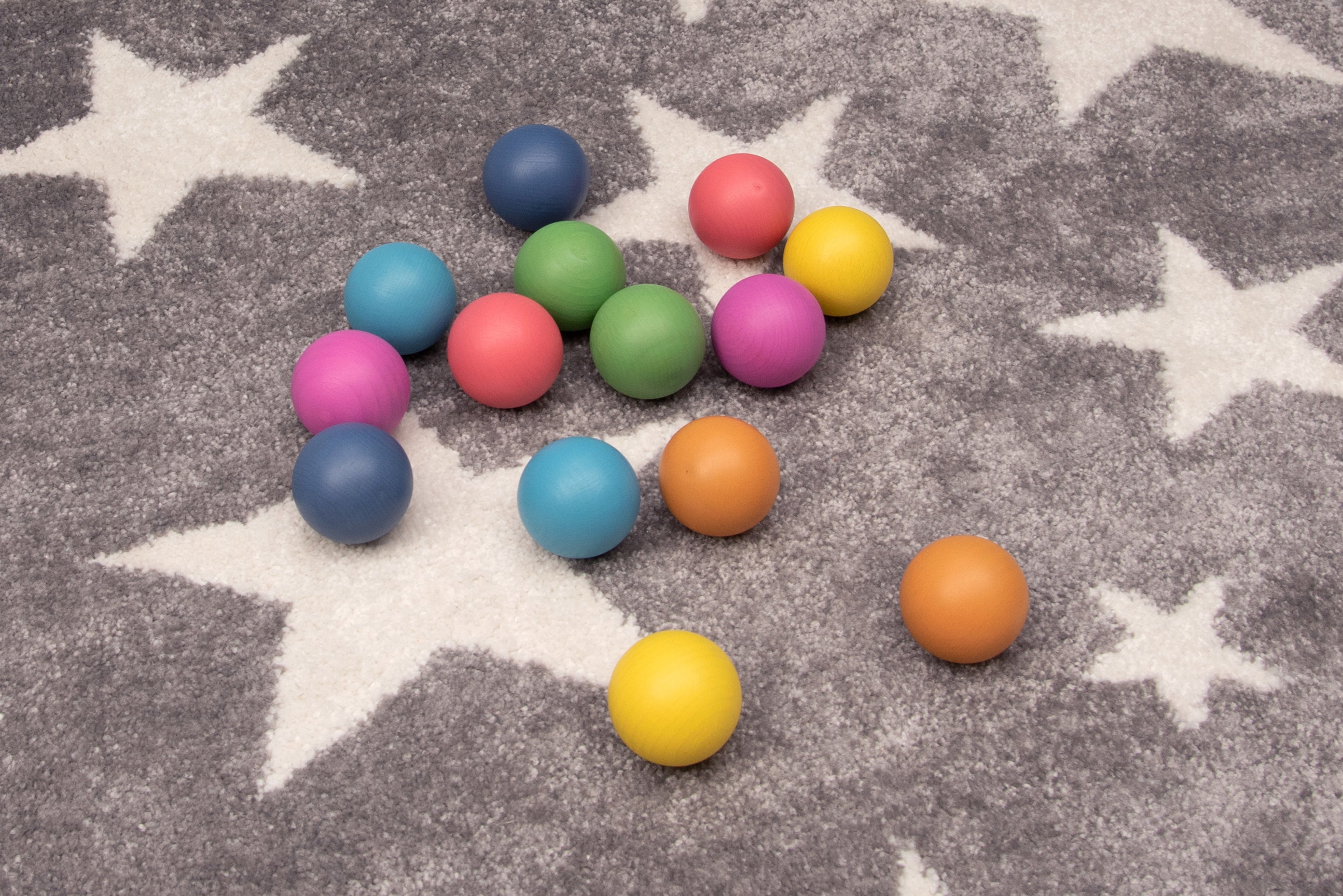 Colorful wooden balls in multiple colors, scattered on a star-pattern rug