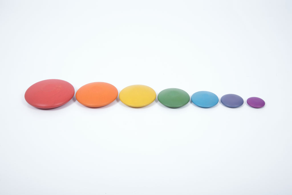 Seven rainbow wooden button disks in a row: red, orange, yellow, green, blue, purple.