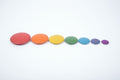 Seven rainbow wooden button disks in a row: red, orange, yellow, green, blue, purple.