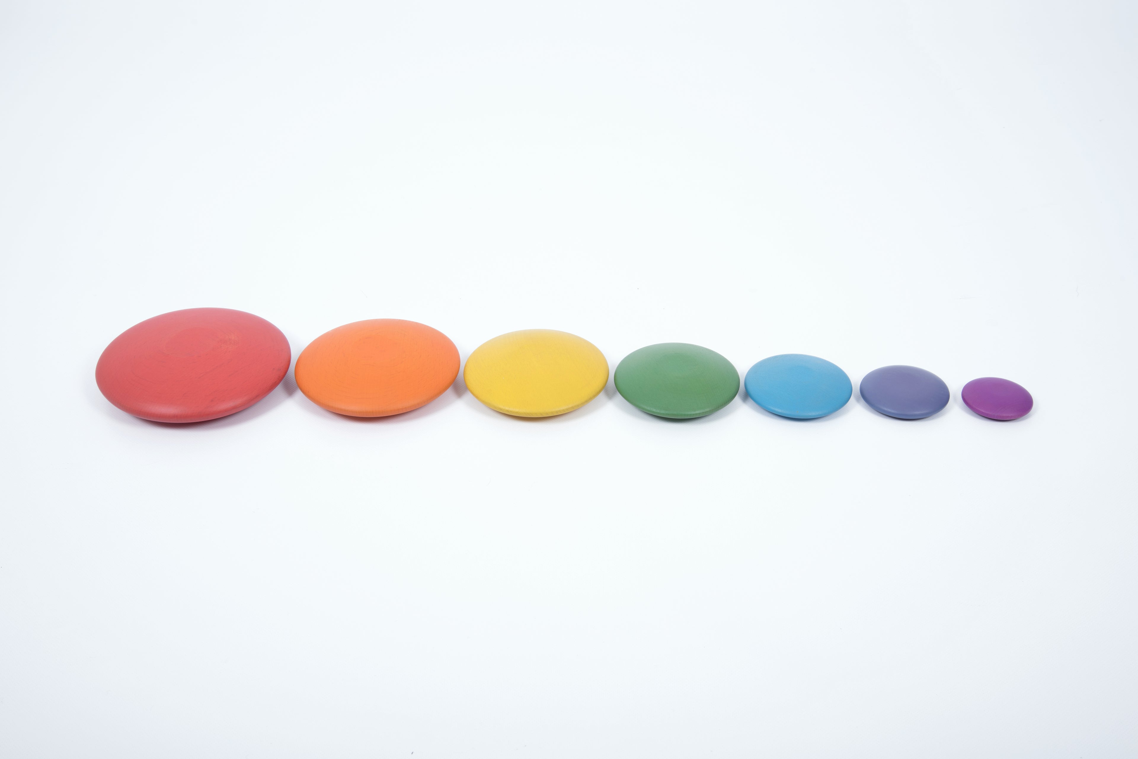 Seven rainbow wooden button disks in a row: red, orange, yellow, green, blue, purple.