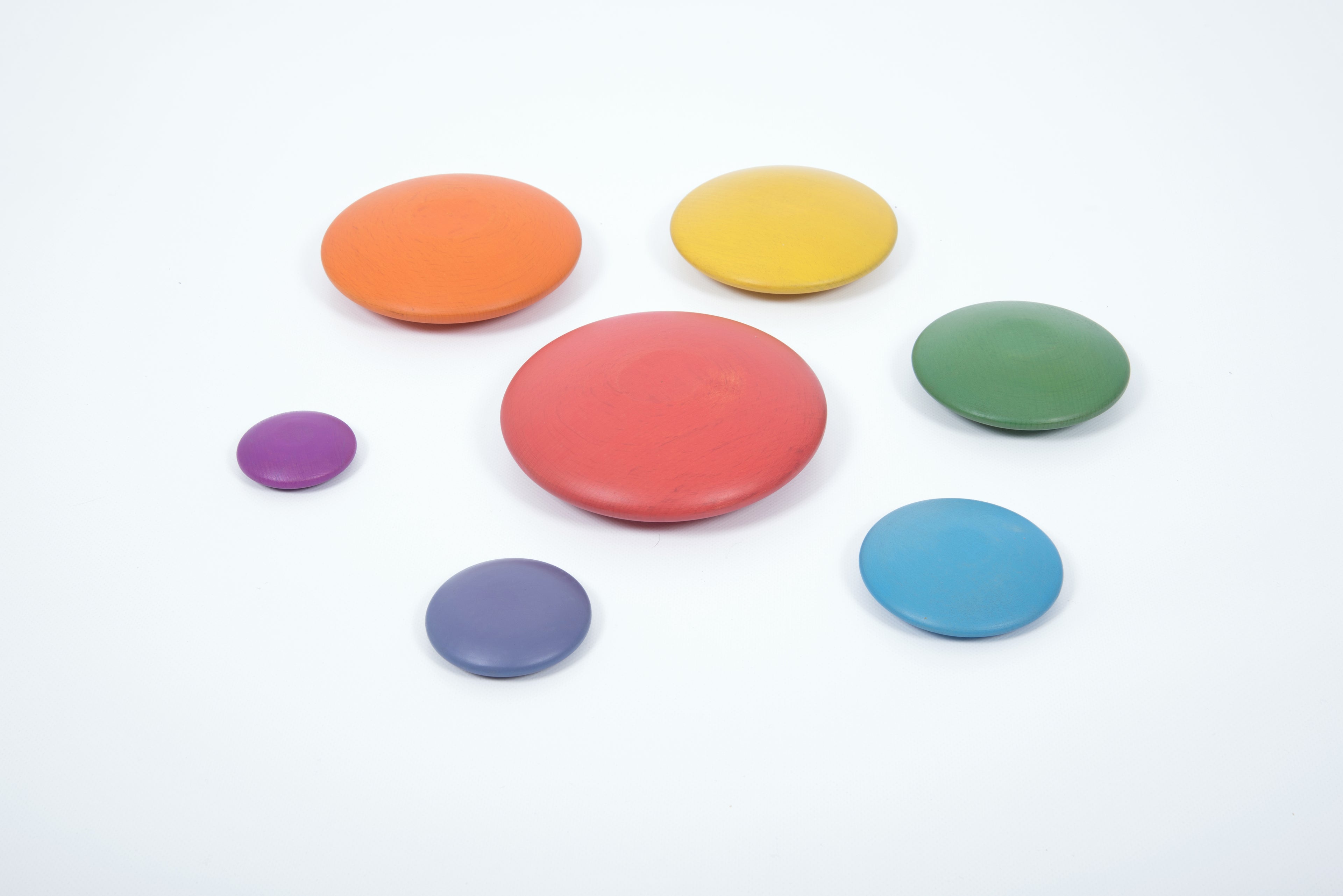 Seven rainbow wooden button disks spread out: red, orange, yellow, green, blue, purple.