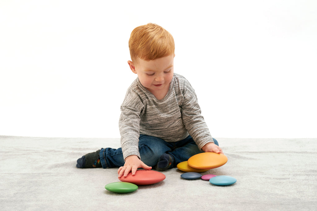 Seven rainbow wooden button disks scattered and partially stacked, multi-color set of 7.