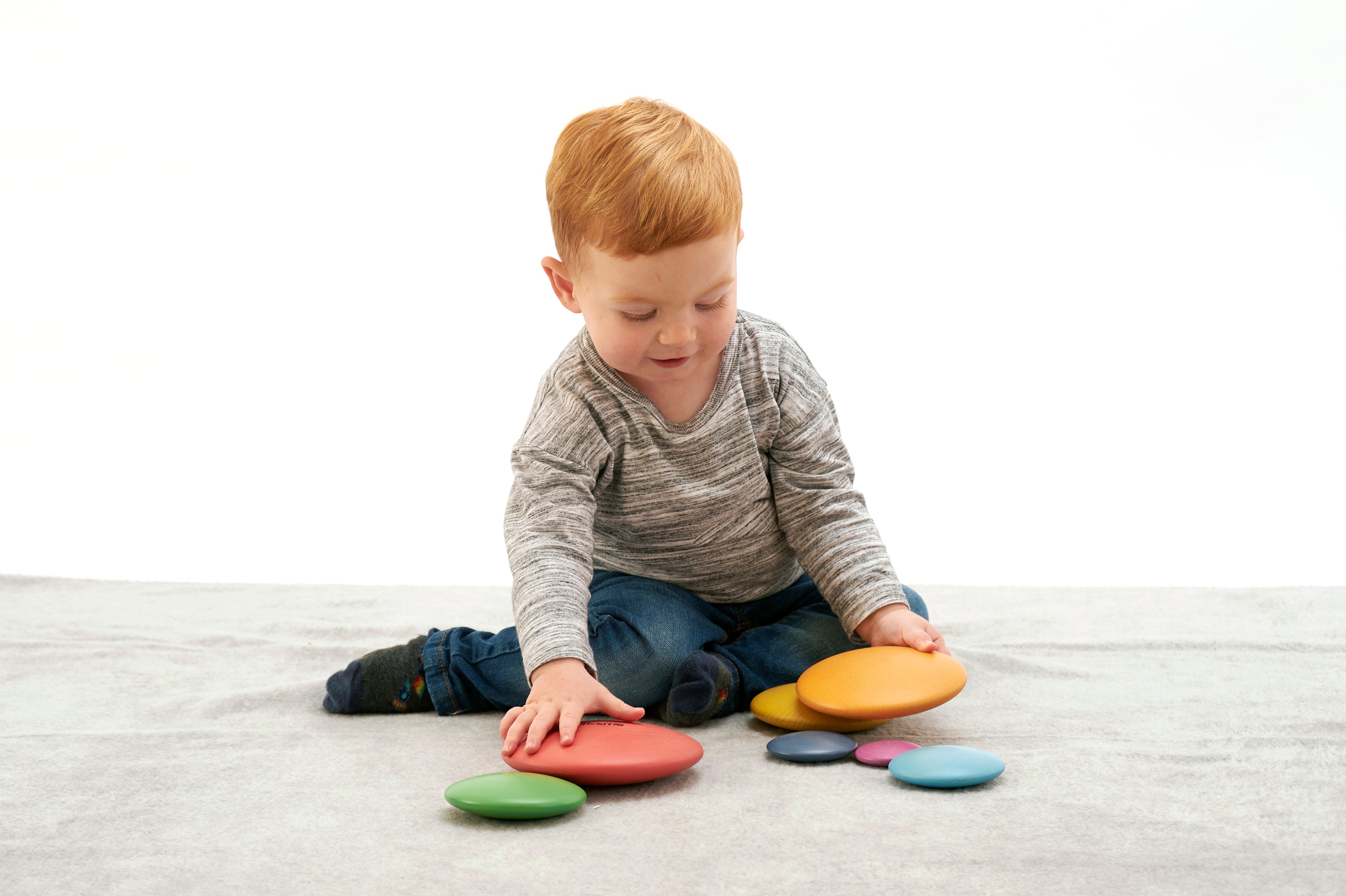 Seven rainbow wooden button disks scattered and partially stacked, multi-color set of 7.