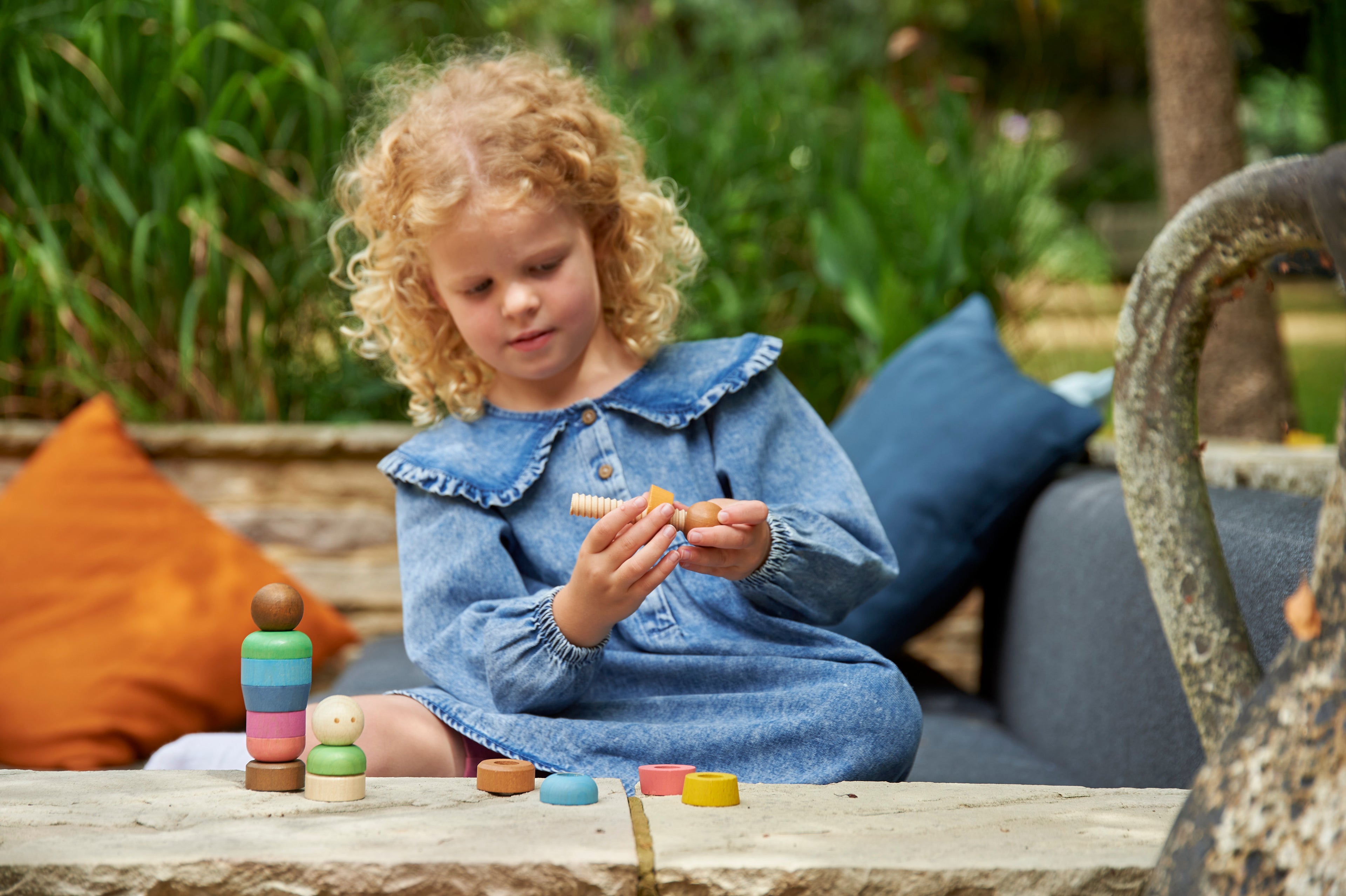 Wooden rainbow peg people toy with colorful stackable pieces on a table