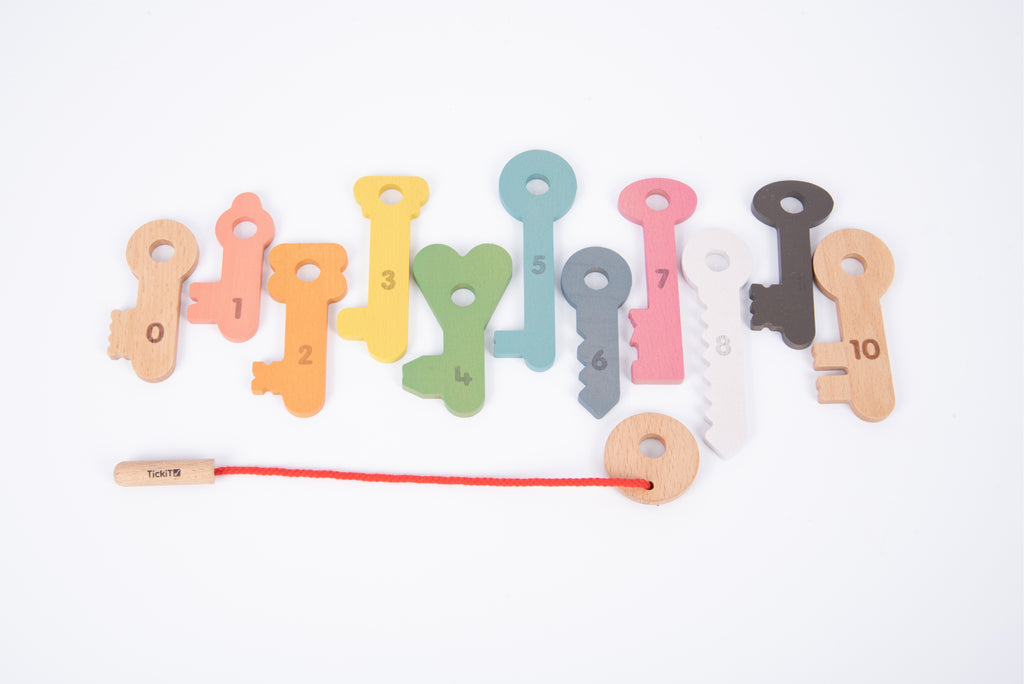 Wooden counting keys arranged in a row, multicolor with printed numbers and red string.