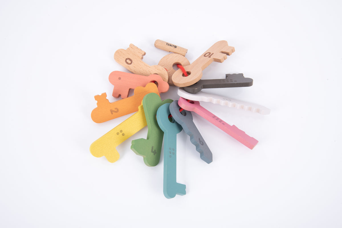 Wooden key pieces and numbered keys in rainbow colors with a red string loop on top.