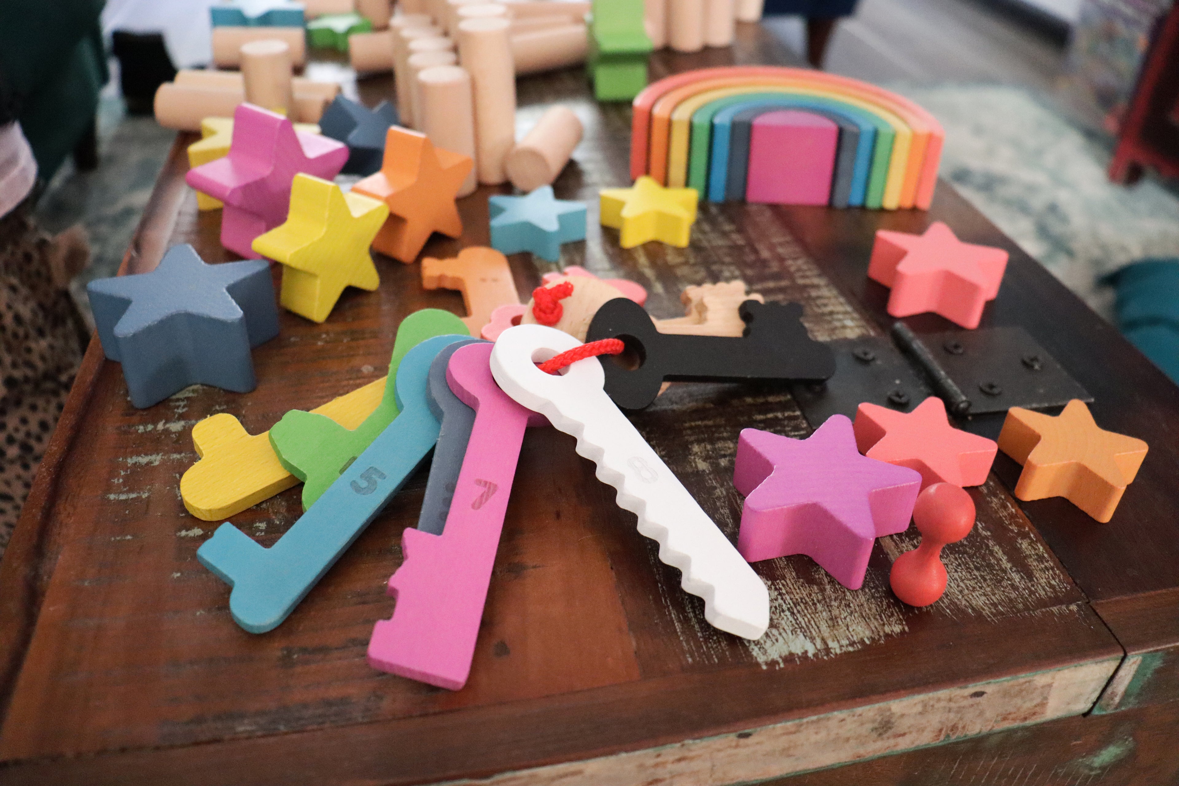 Rainbow wooden counting keys and star-shaped pieces on a tabletop with a red string loop.
