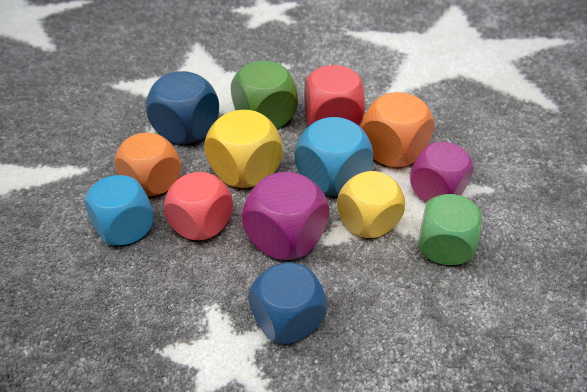 Rainbow wooden cubes scattered on a rug, multicolored small square blocks