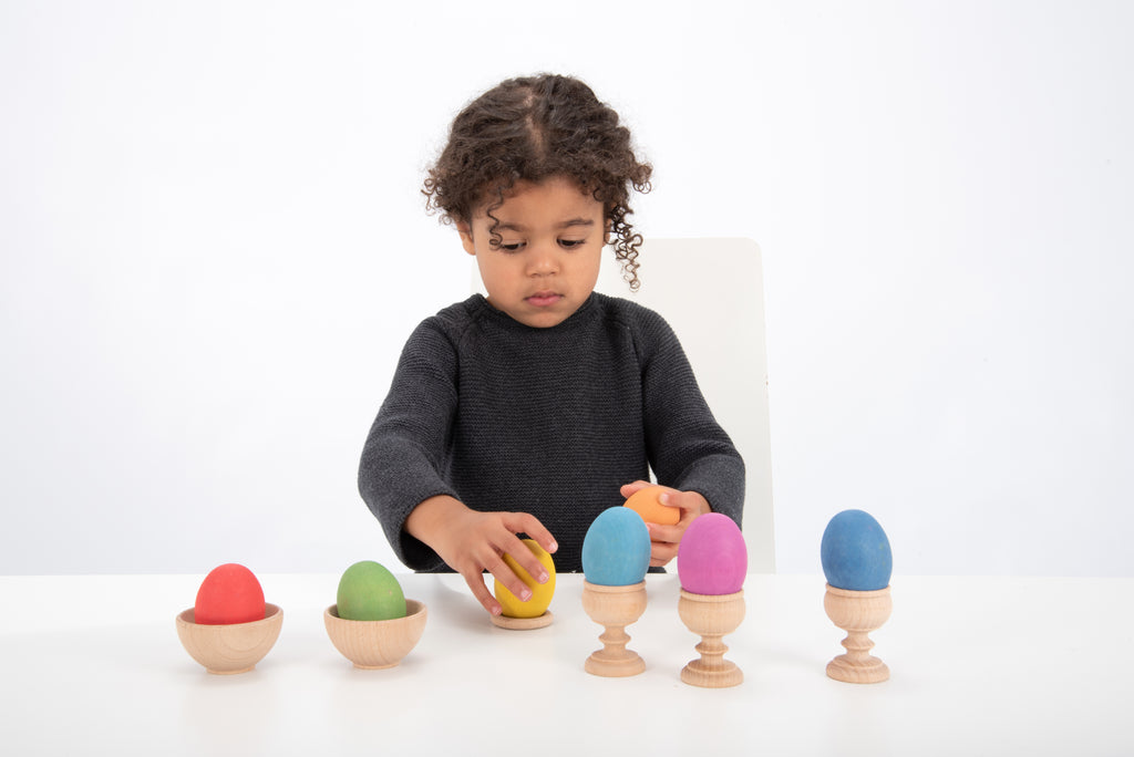 Multicolor wooden eggs and child holding one egg