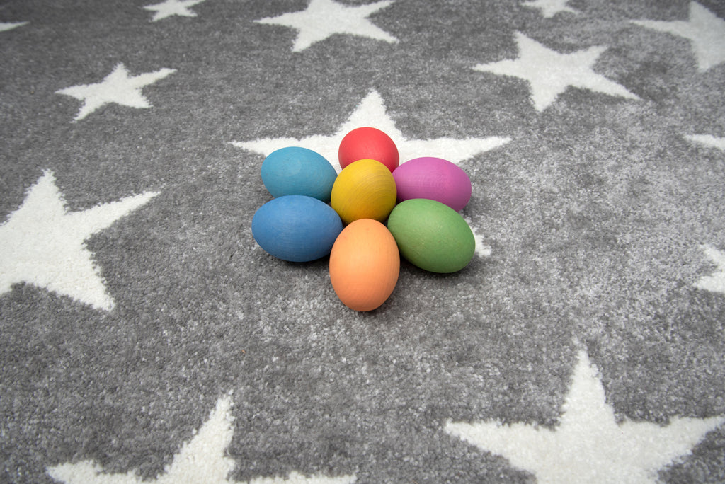Multicolor wooden eggs on a gray star-pattern rug