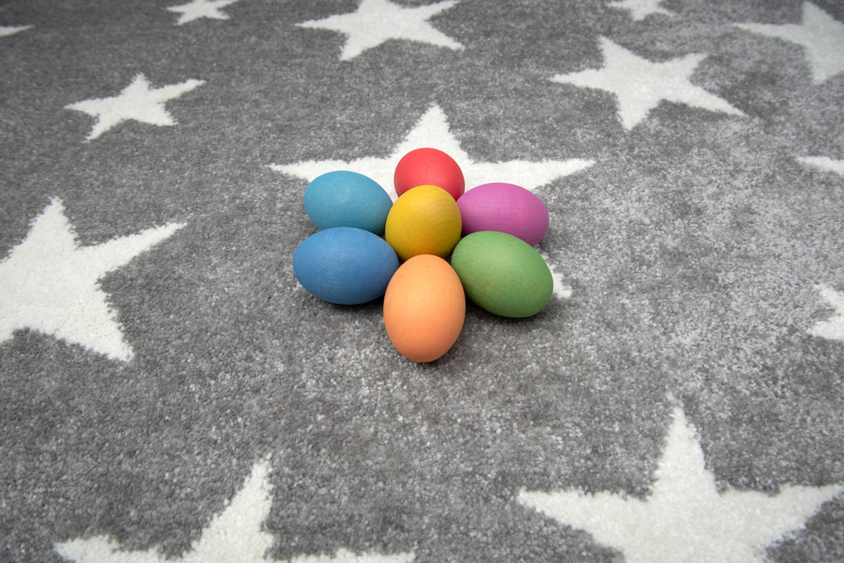 Multicolor wooden eggs on a gray star-pattern rug
