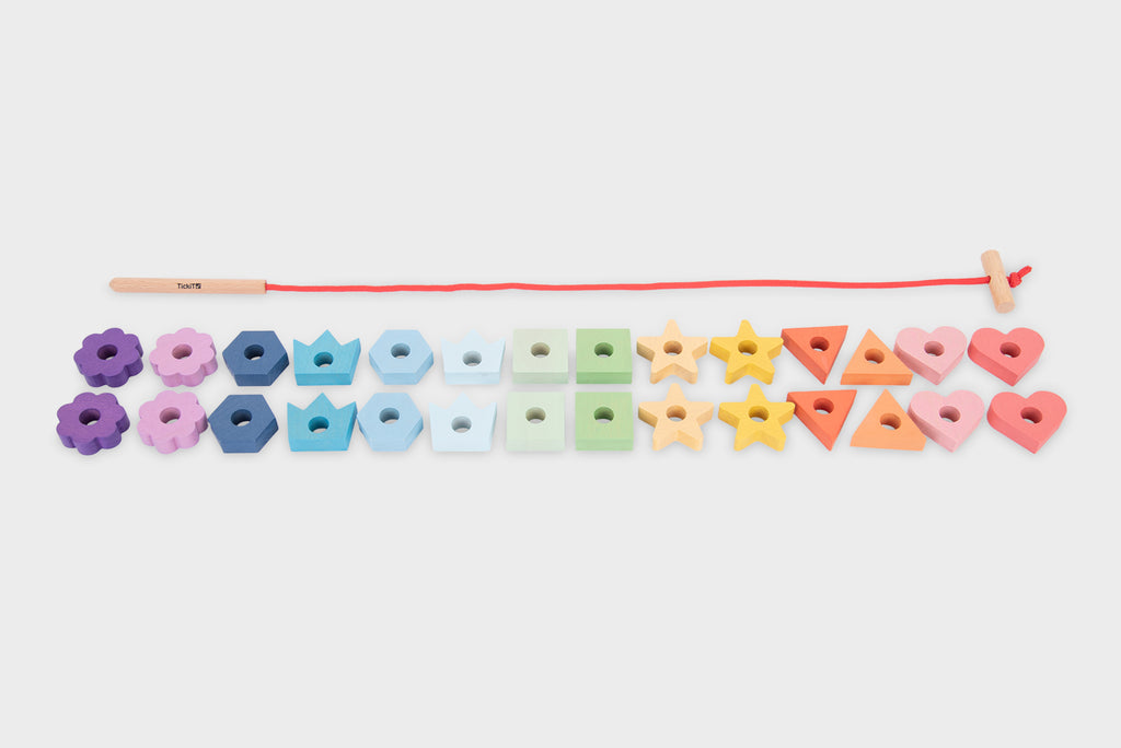 Rainbow wooden lacing shapes with colorful blocks lined up along a red cord