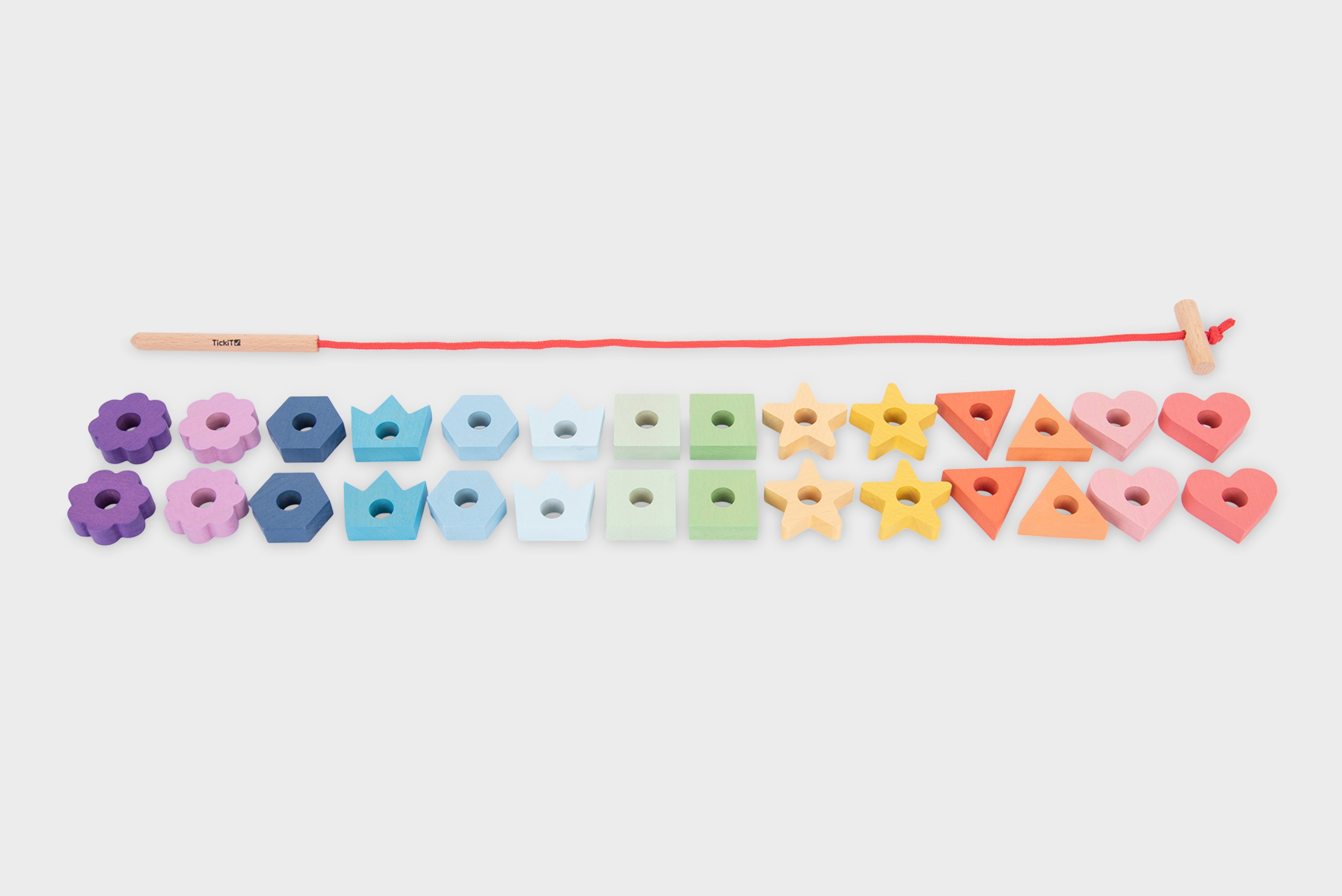 Rainbow wooden lacing shapes with colorful blocks lined up along a red cord