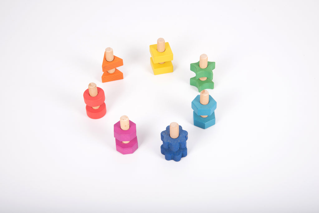 Rainbow wooden nuts and bolts on white: scattered rainbow screws and block nuts.