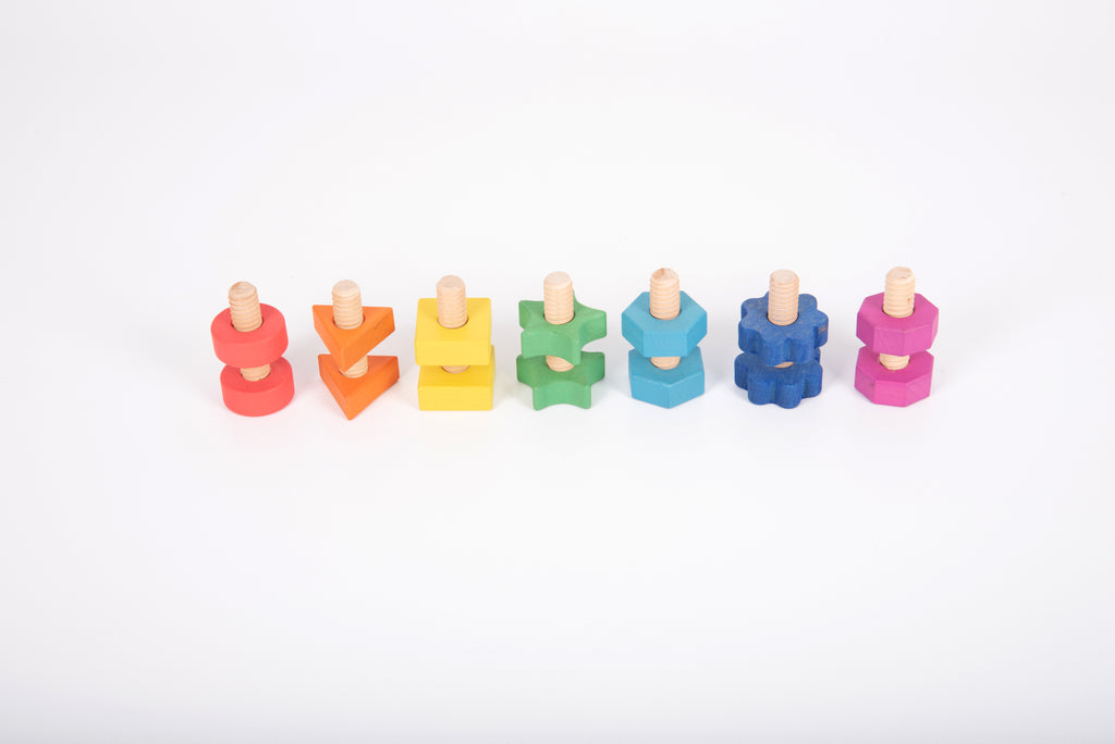 Rainbow wooden nuts and bolts on white: colorful threaded pieces grouped in a line.