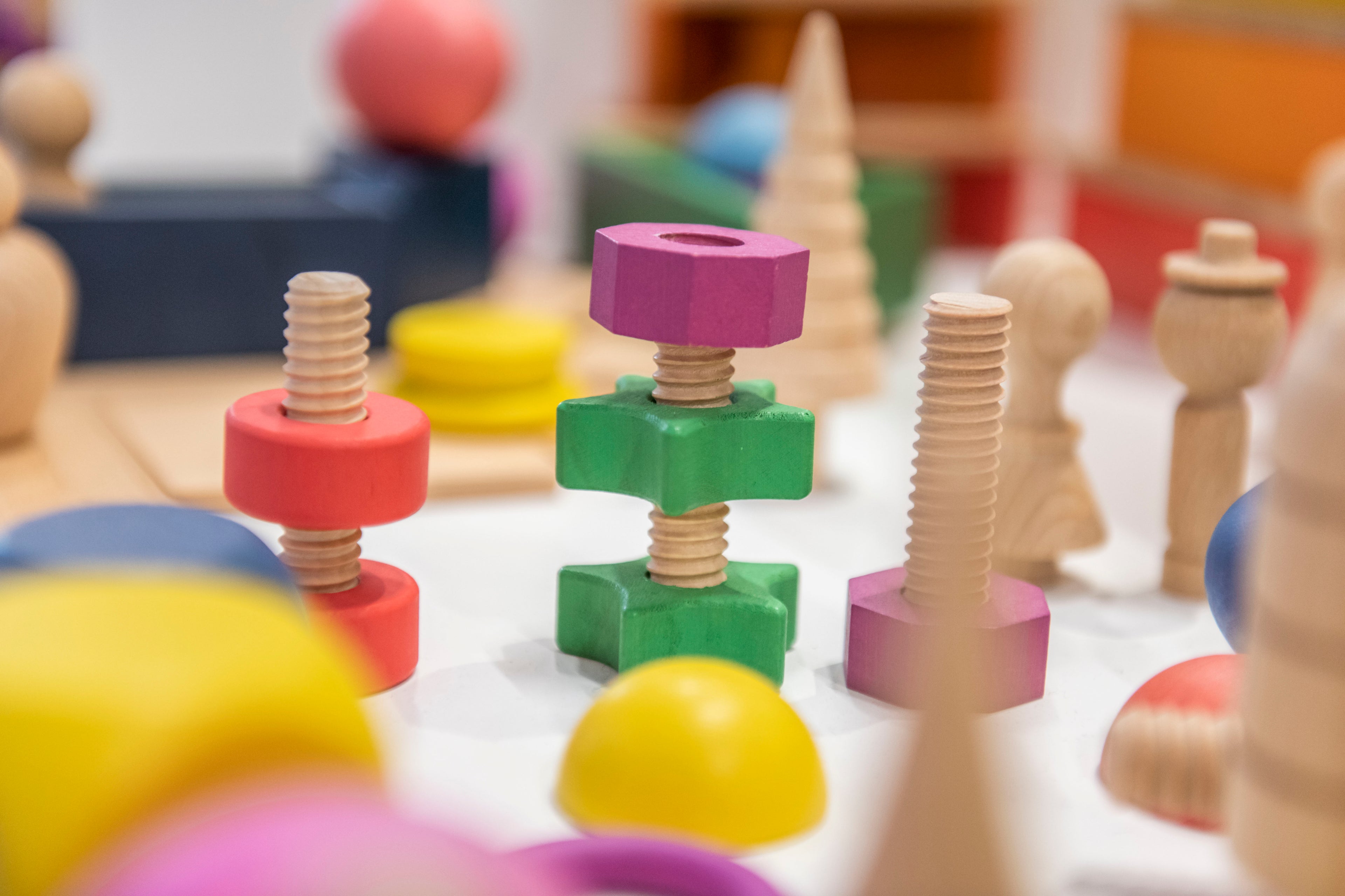 Rainbow wooden nuts and bolts: colorful threaded screws with matching wooden block nuts.
