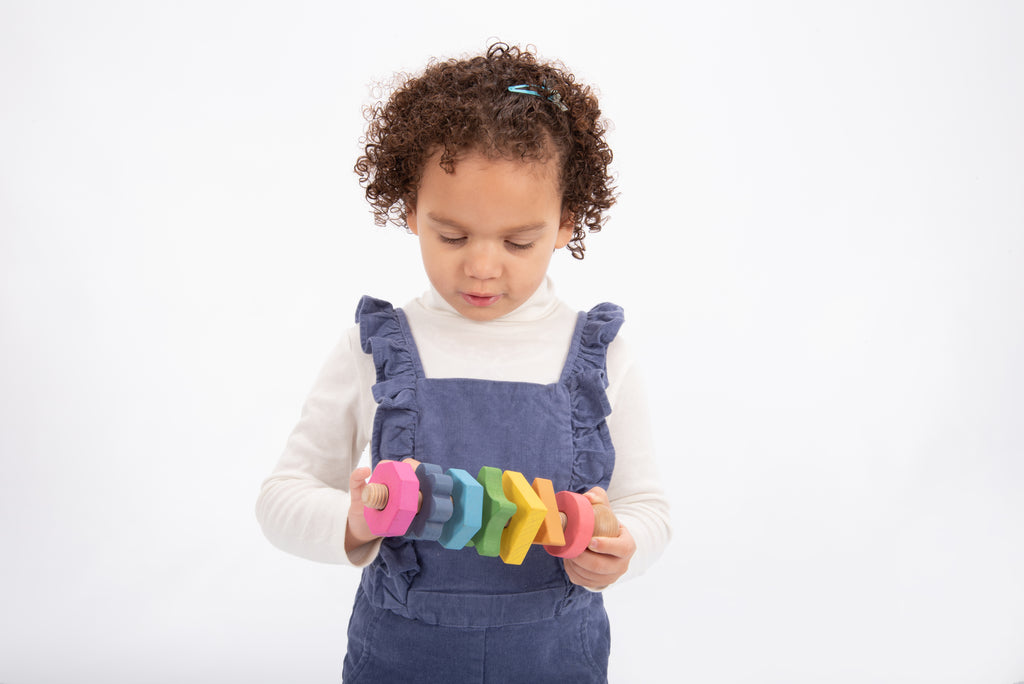 Rainbow wooden shape twister with colorful wooden blocks and stacked rings in hands