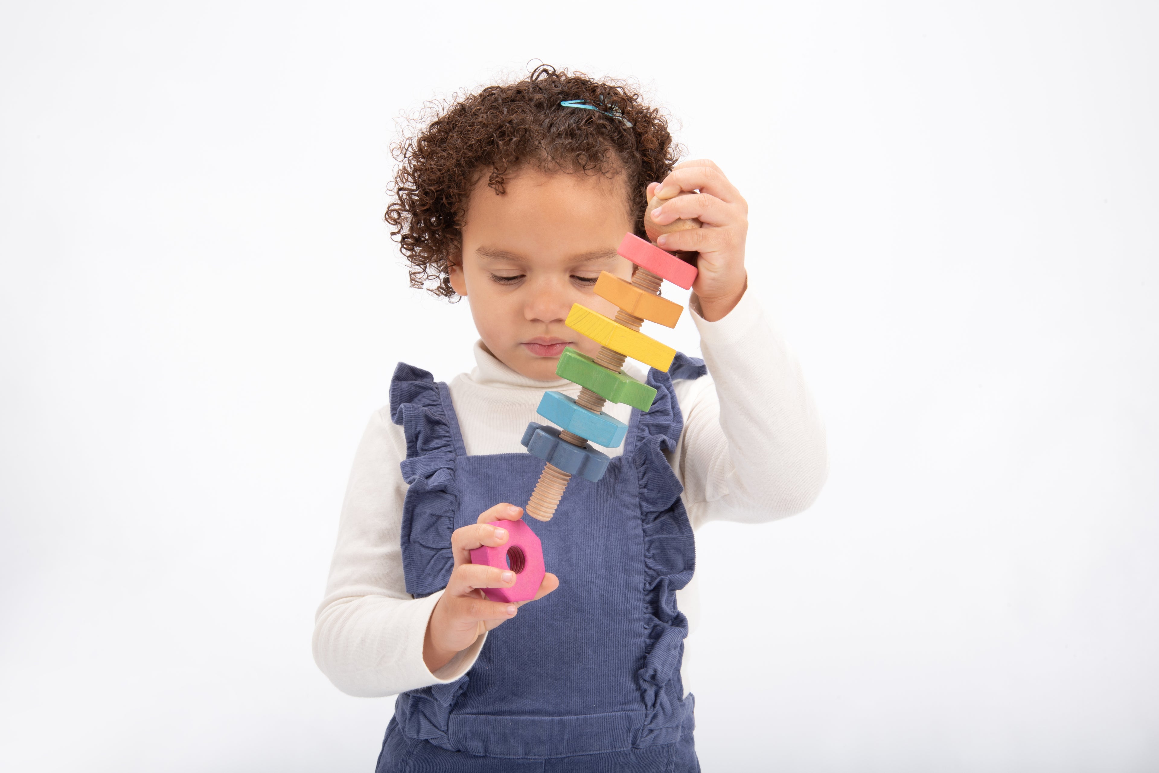 Rainbow wooden shape twister toy: child holding colorful stacked wooden blocks