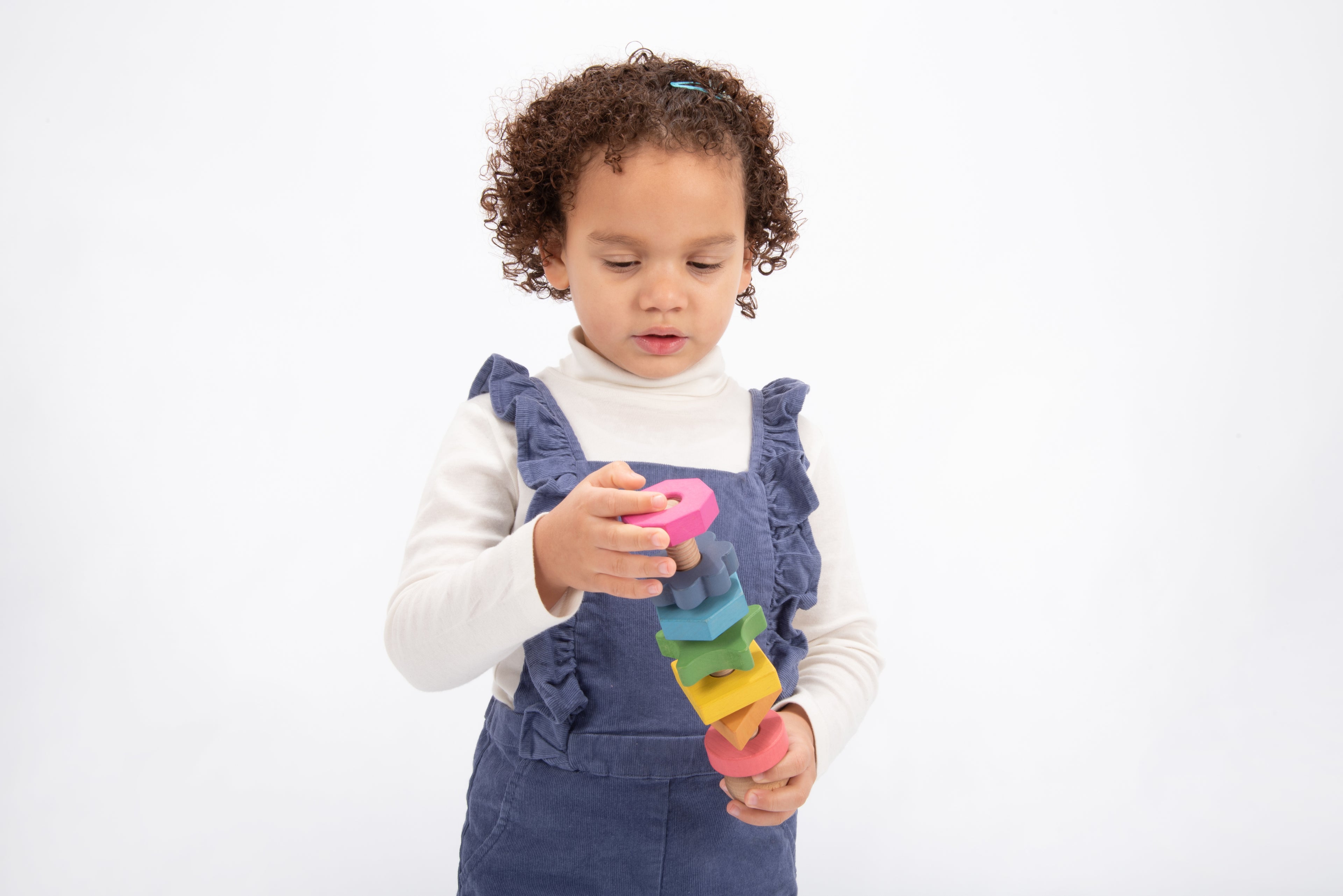 Rainbow wooden shape twister toy with stacked colorful blocks, held in hands