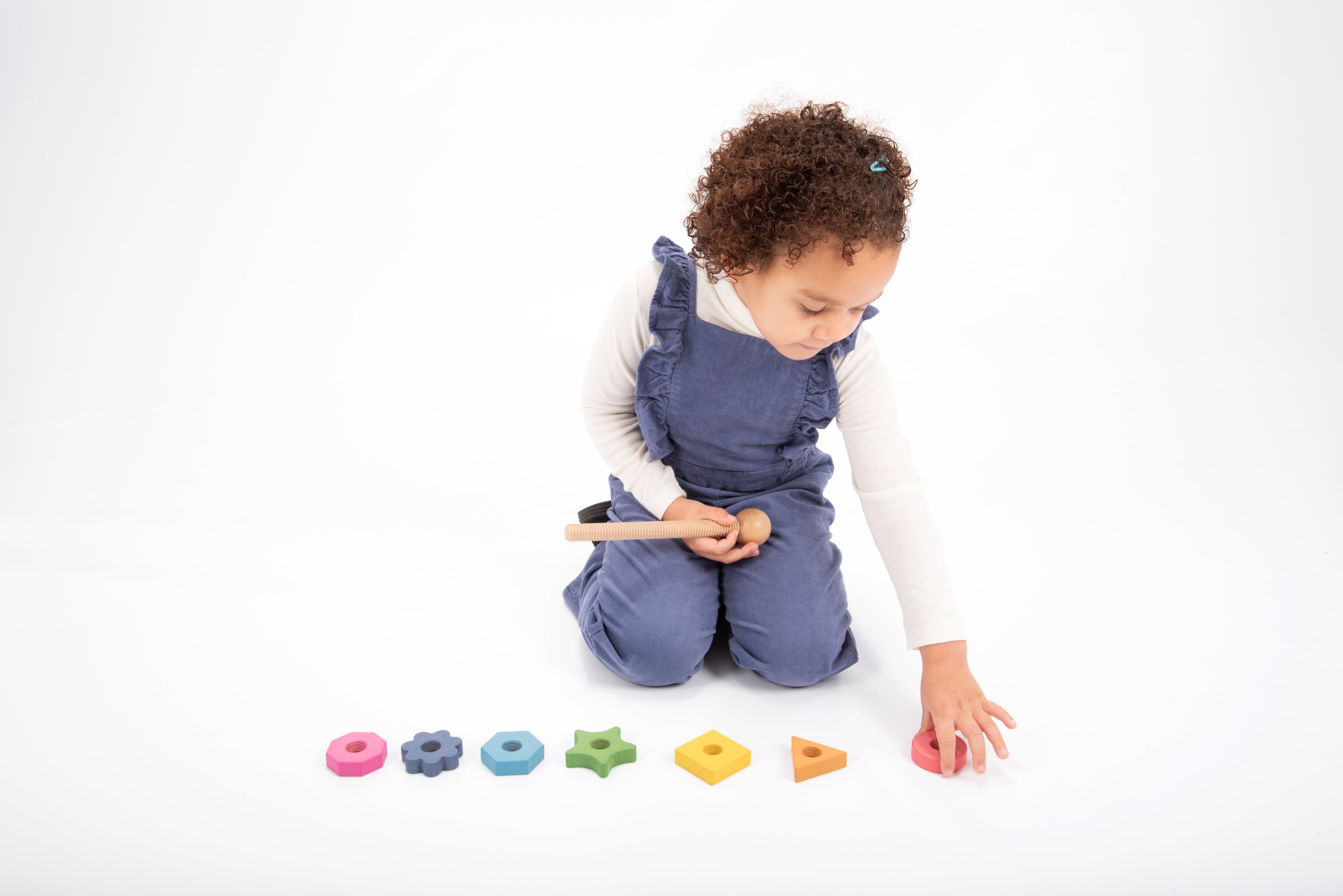 Rainbow wooden shape twister pieces on the floor: colored stacked rings and blocks