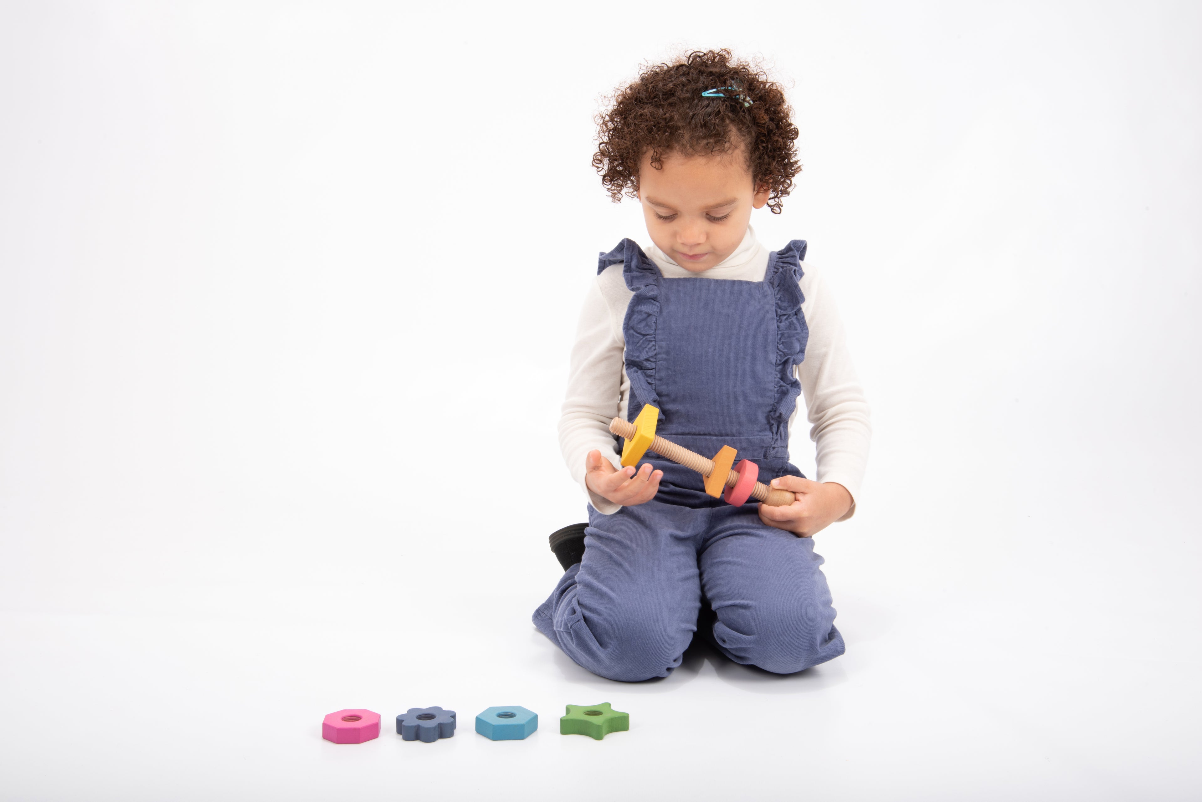Rainbow wooden shape twister toy with rainbow blocks being held by a child
