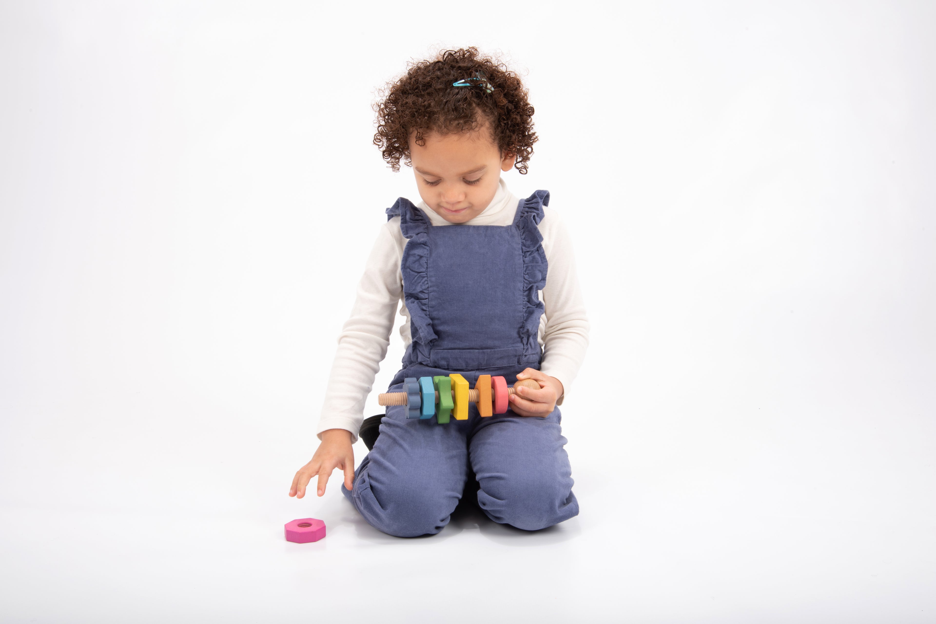 Rainbow wooden shape twister toy with multicolor blocks held in front of child