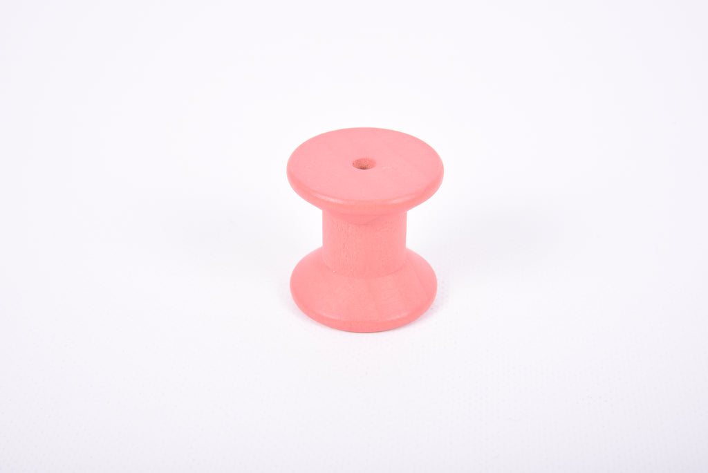 Single pink wooden thread spool with flat round top and base