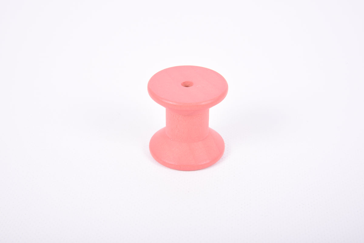 Single pink wooden thread spool with flat round top and base