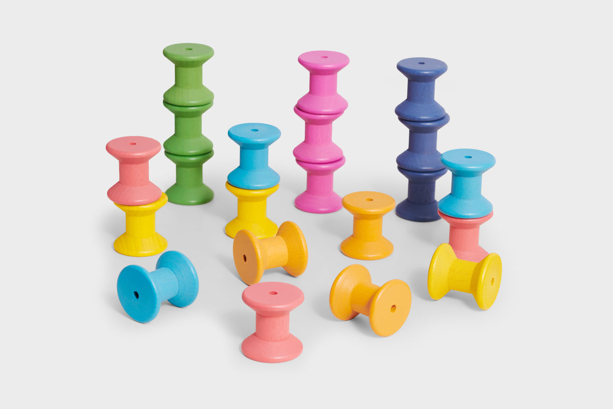 Rainbow wooden thread spools in mixed pastel colors, clustered together