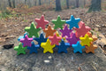 Rainbow wooden star blocks on a weathered wooden log outdoors