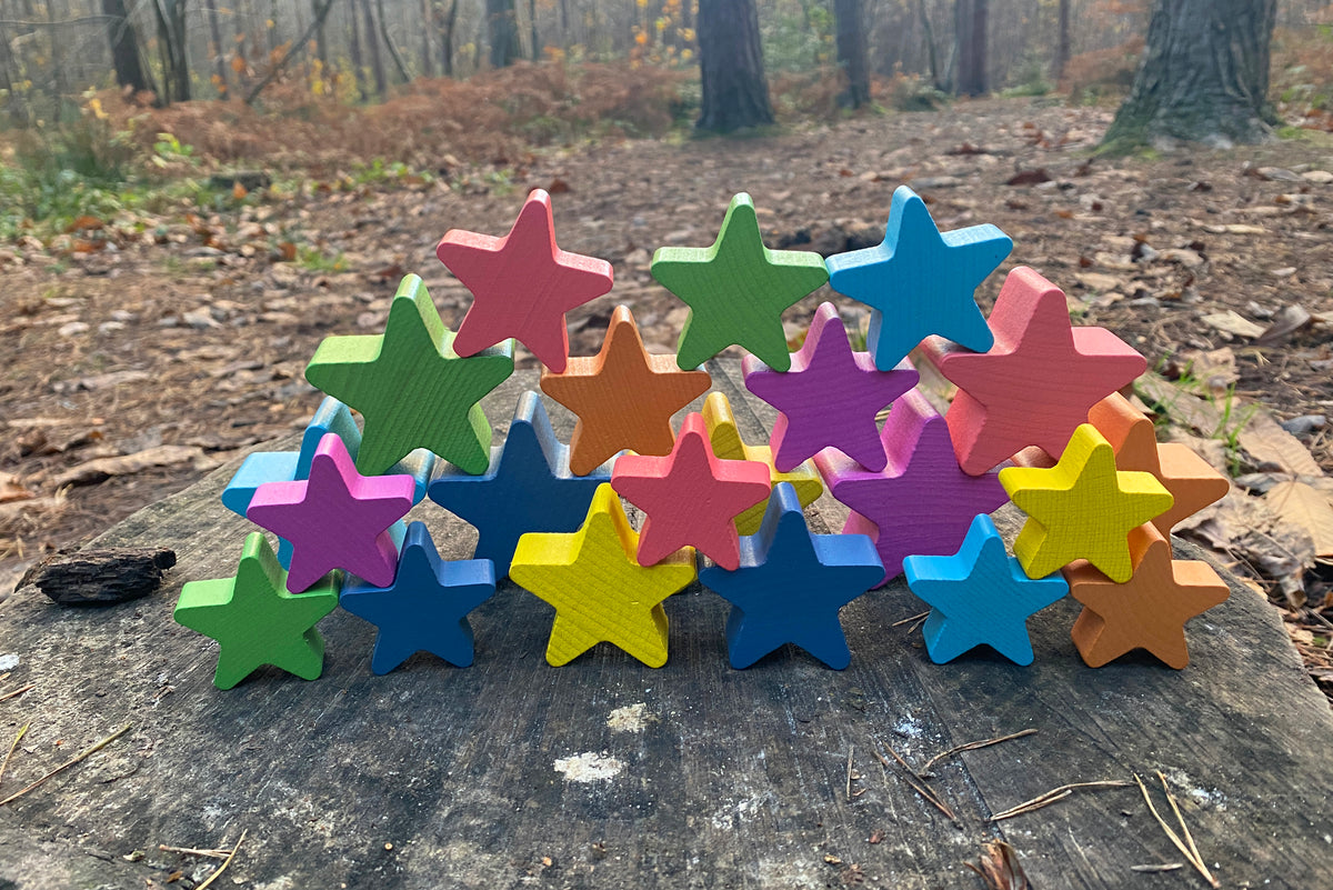 Rainbow wooden star blocks on a weathered wooden log outdoors