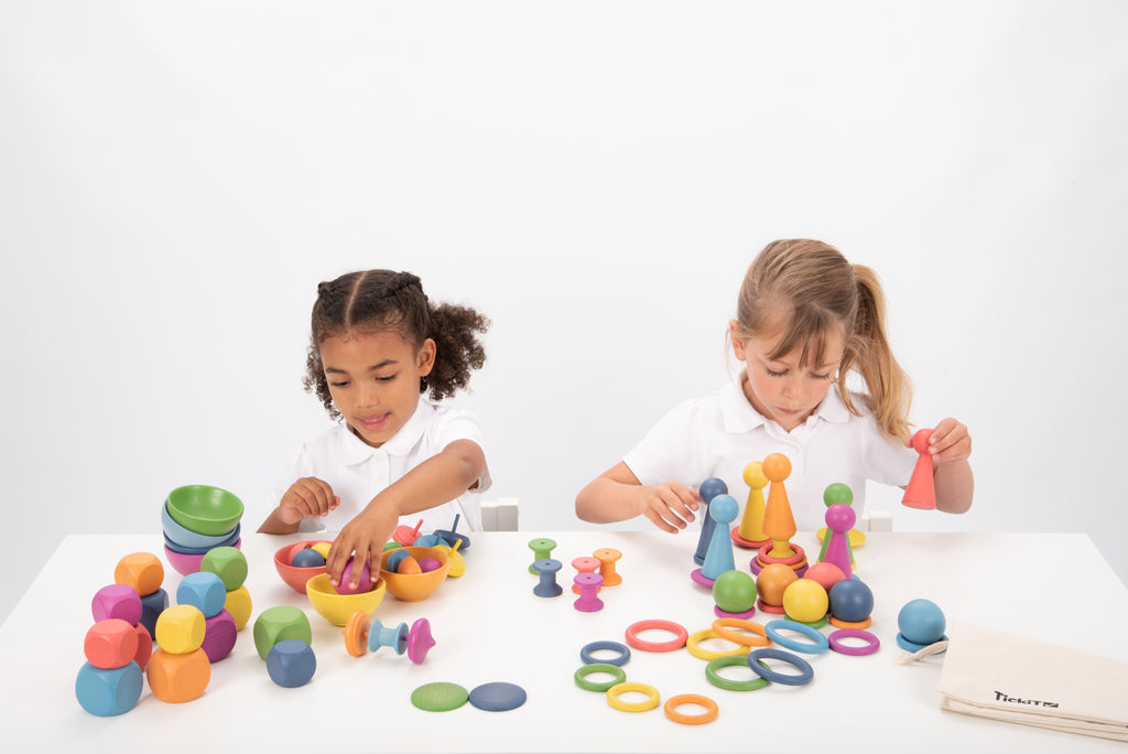 Wooden rainbow toy set with multicolor rings, pegs, balls and cones on tabletop