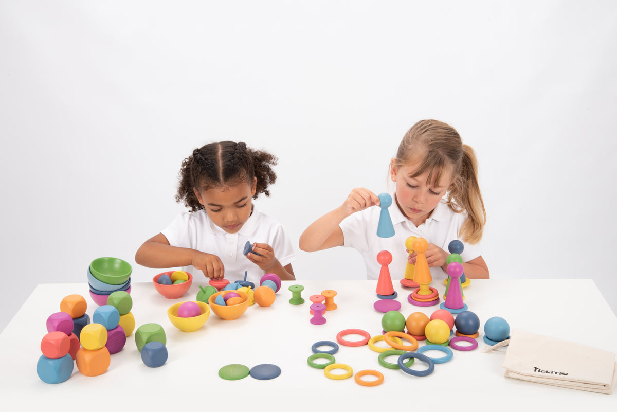 Wooden rainbow toy set with colorful pegs, rings, balls and bowls arranged for play