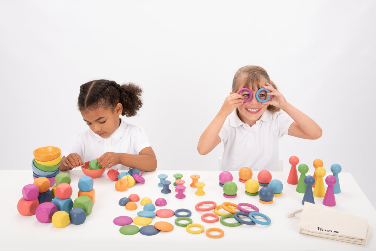Wooden rainbow toy set with colorful rings, pegs, balls and stacking pieces on table