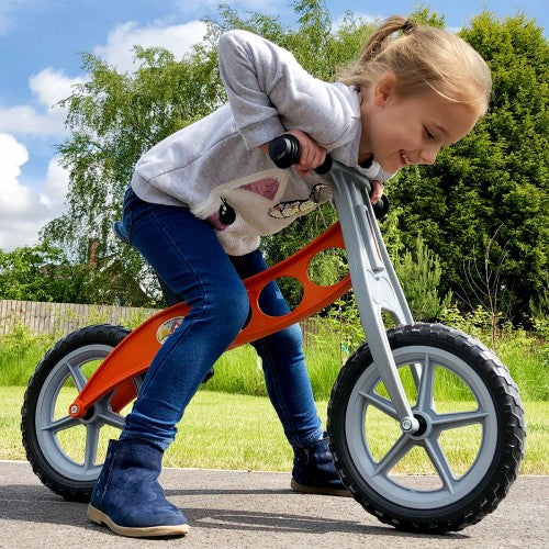Lightweight balance bike with orange frame, black tires, and gray spoked wheels