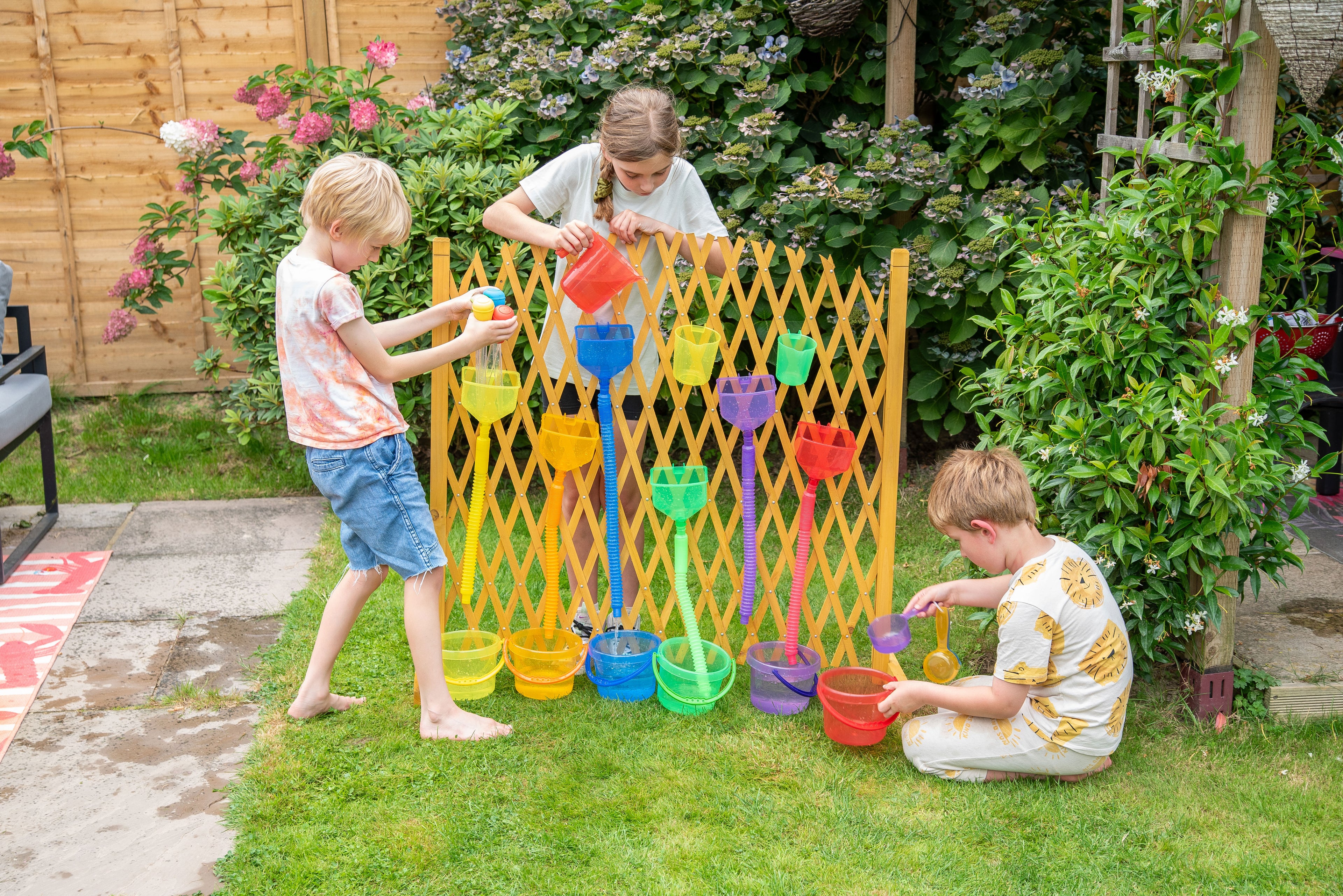 Yellow water play gate with hanging cups; kids pouring water