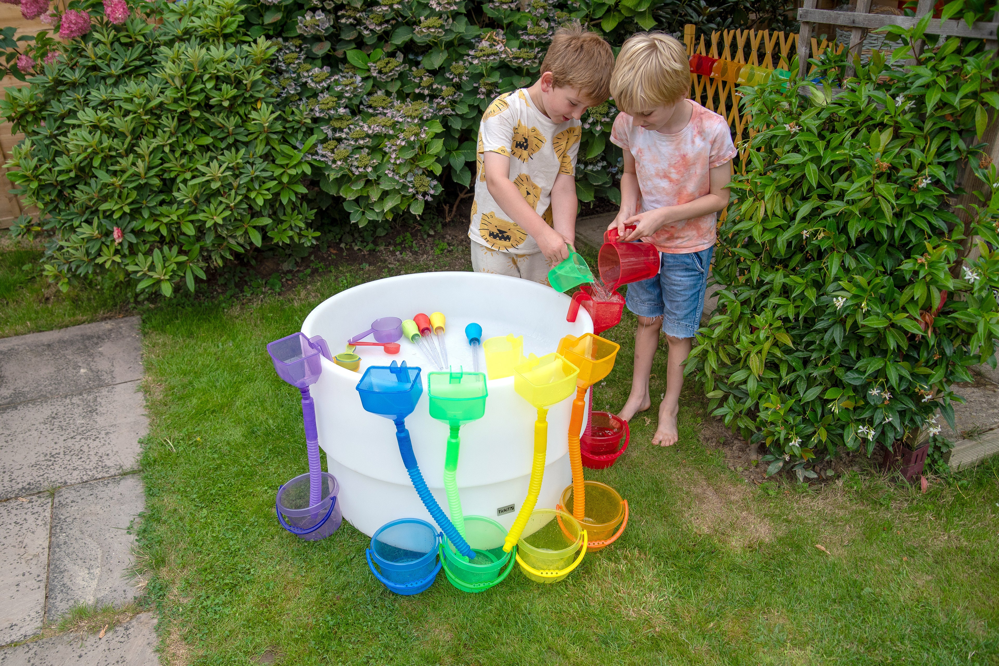Round sand and water table with colorful buckets and cups, kids using tools