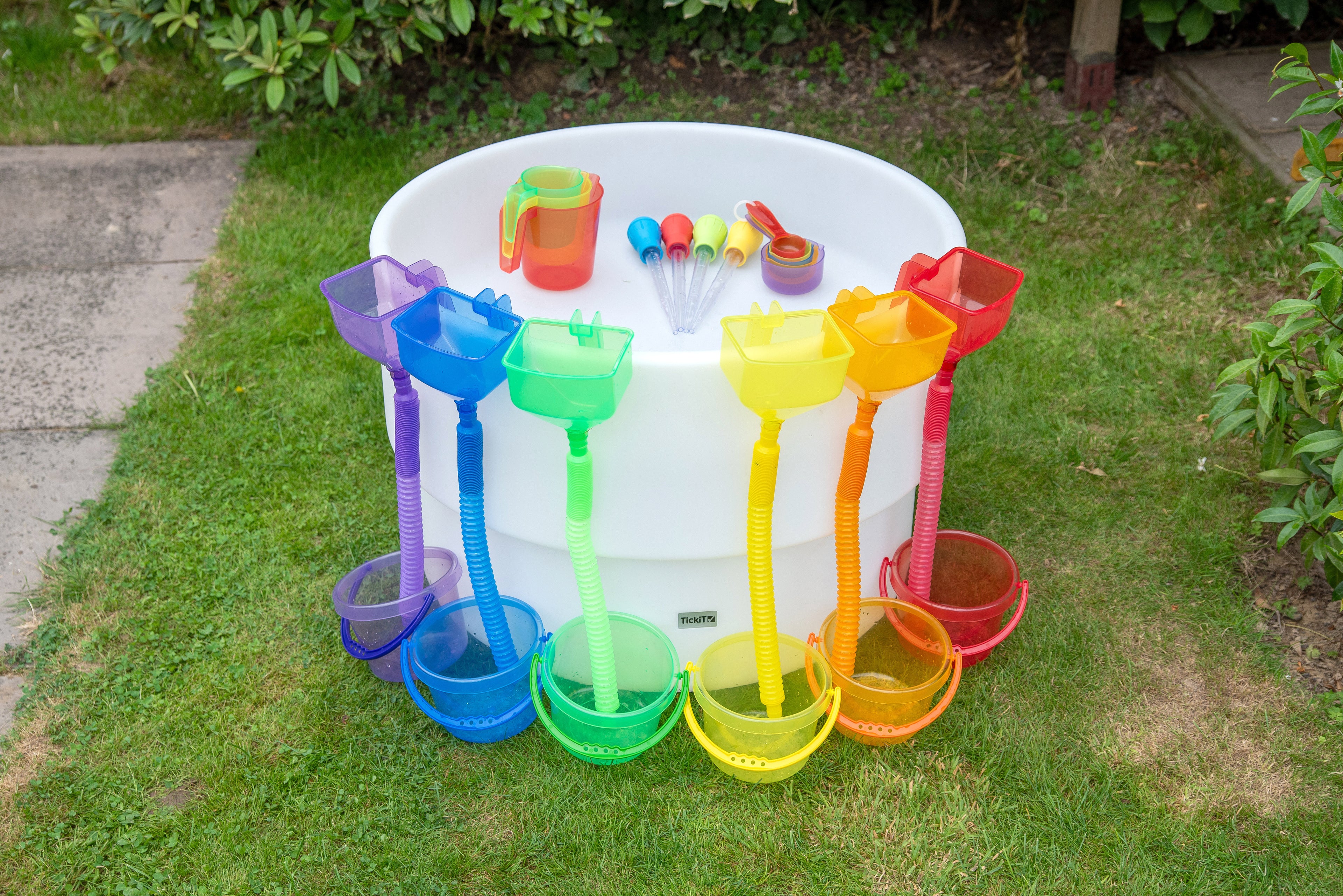 Outdoor round sand and water table with colorful scoops, cups, and hoses