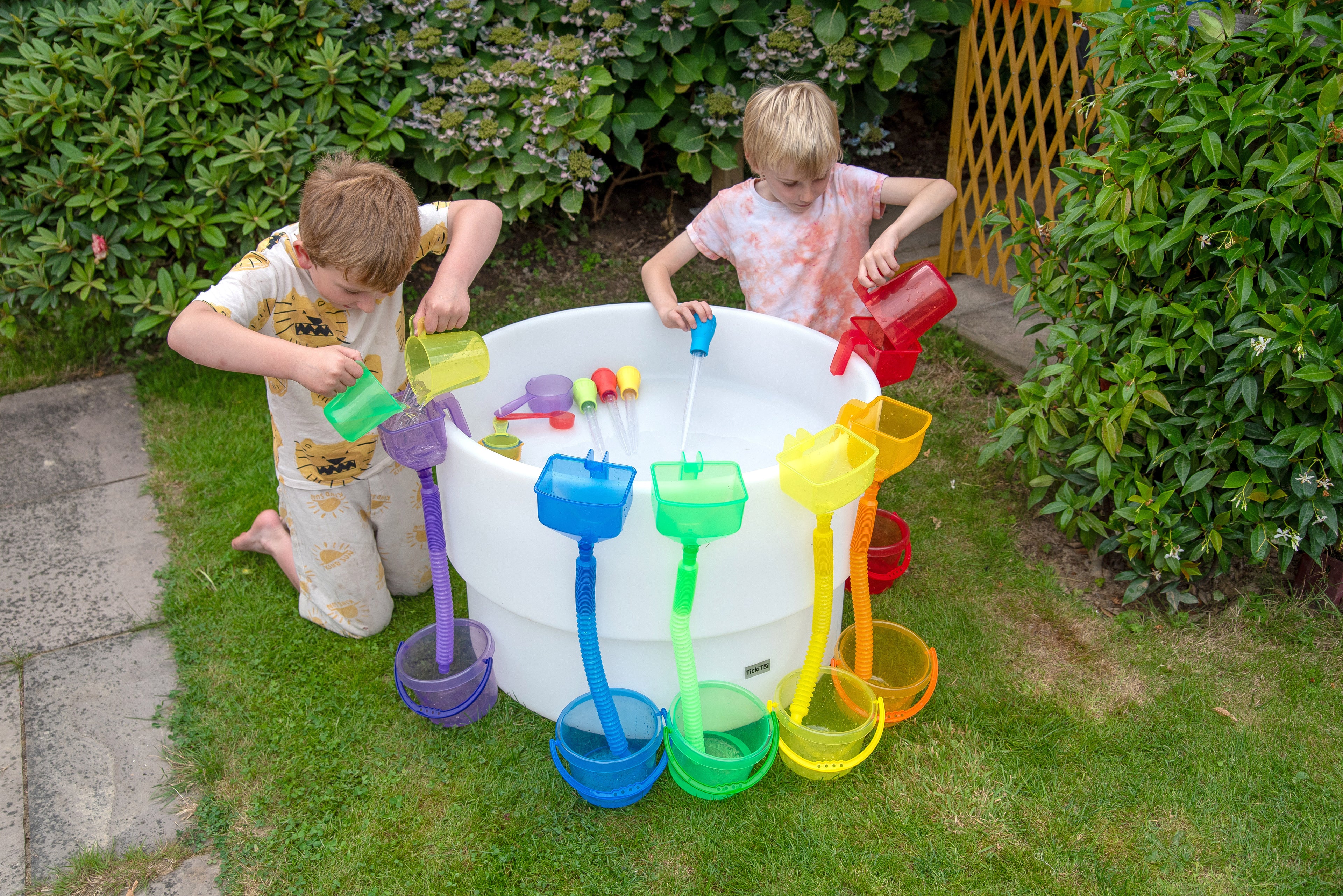 Round sand and water table with rainbow tools as kids pour and play