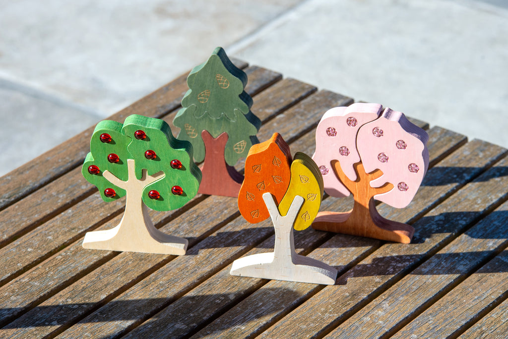 Colorful wooden tree shapes with gem-like dots and painted trunks on a bench