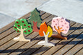Colorful wooden tree shapes with gem-like dots and painted trunks on a bench