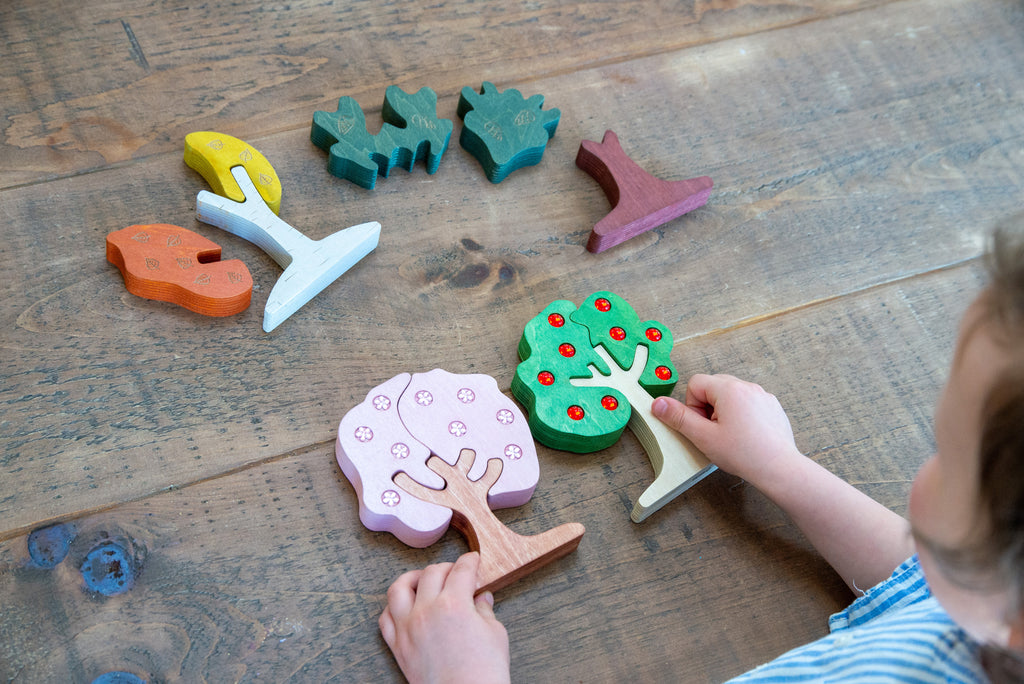 Wooden gem tree puzzle set with green, purple, and orange trees in a toddler play layout