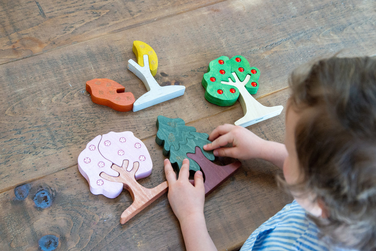 Kid hands arranging colorful wooden gem tree pieces on a wooden surface
