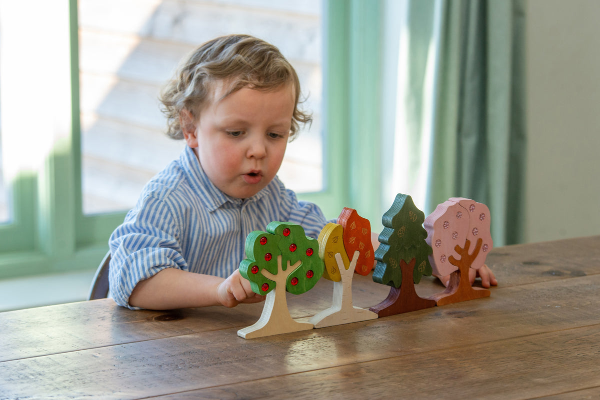 Set of colorful wooden tree cutouts with painted gems on a tabletop, child playing