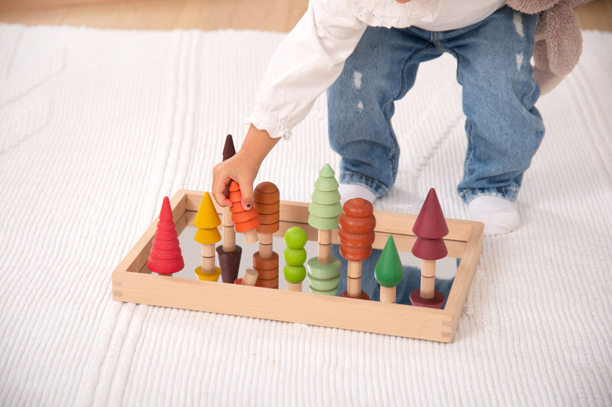 Wooden tree figures standing on rectangular tray for stacking play