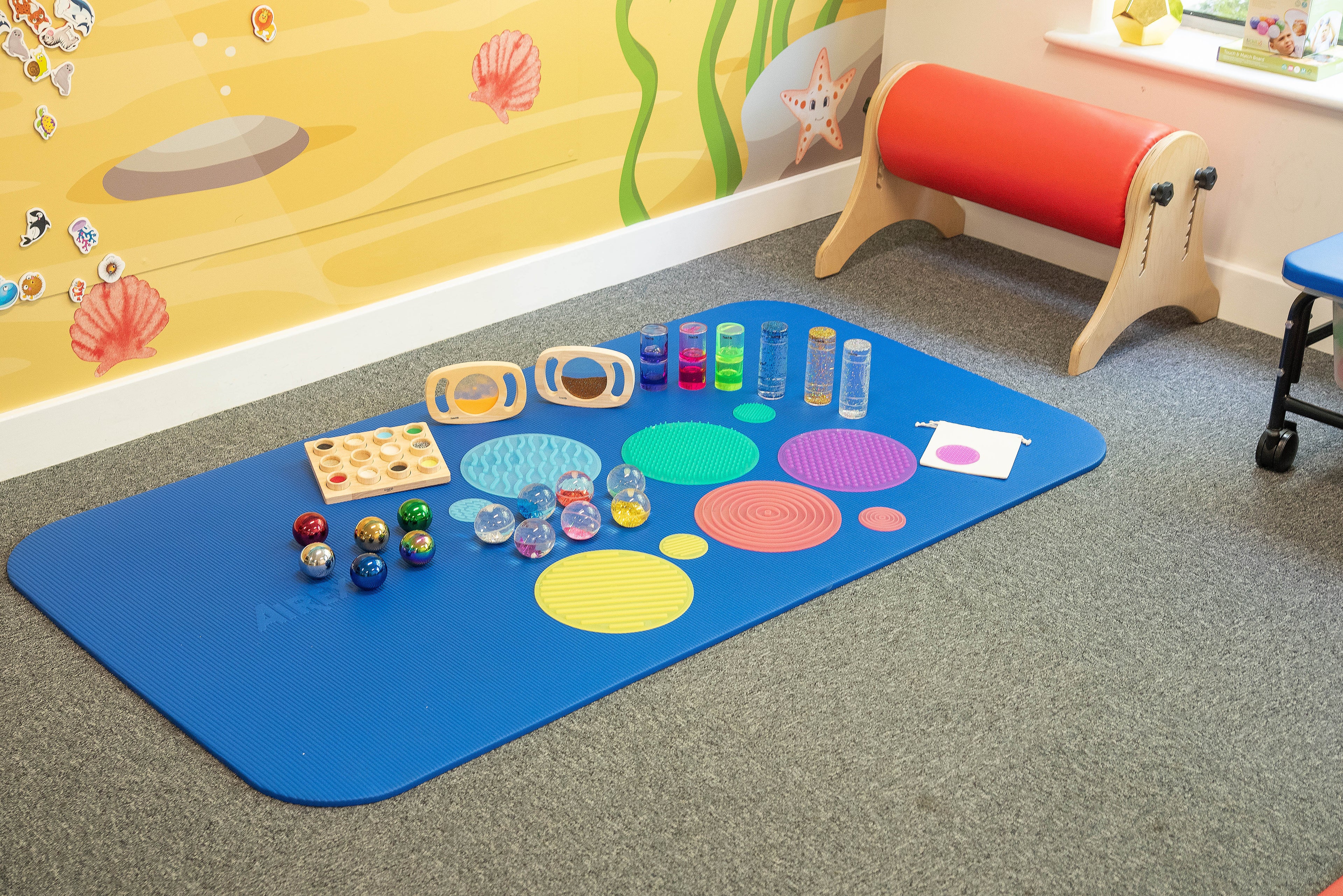 Floor sensory activity mat with colorful textured circles, jars, and bead balls
